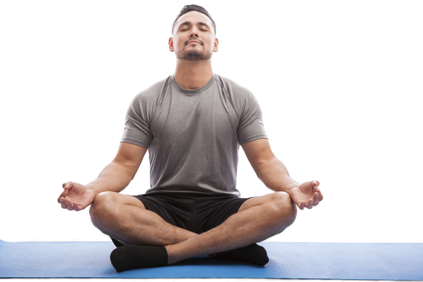 Young man in sporty outfit doing yoga and meditating on an exercise mat against a white background